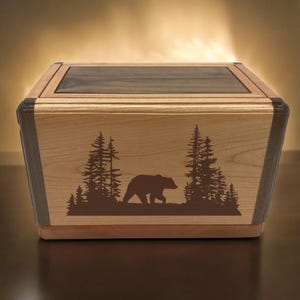 以下が含まれることがあります： クマと木のデザインが施された木製の箱。箱はメープルとウォールナットの木材で作られており、濃い茶色のステインが塗られています。