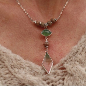 May include: A silver chain necklace with brown wooden beads and two green and pink gemstone pendants.