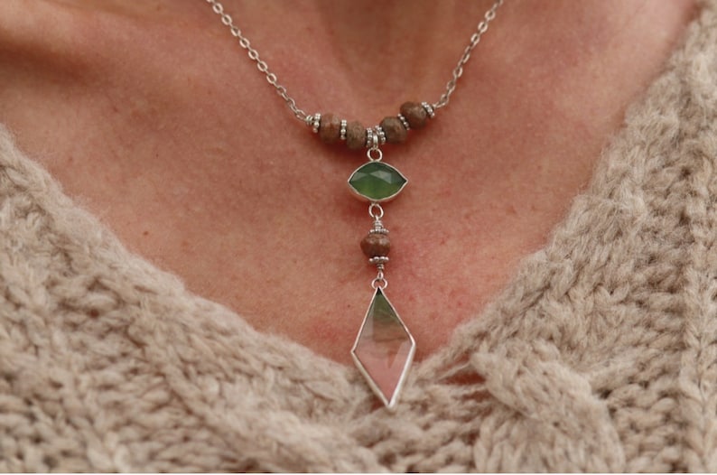 May include: A silver chain necklace with brown wooden beads and two green and pink gemstone pendants.