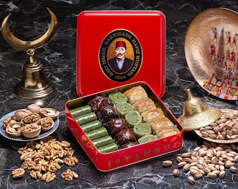 May include: A red box with a gold lid containing a variety of baklava pastries. The box has a gold label with the text "HACI ISMAIL HAKKIZADE  HAFIZ MUSTAFA 1864 ISTANBUL". The box is surrounded by walnuts, pistachios, and other decorative items.