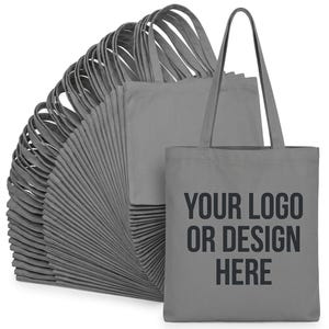 May include: A large stack of grey tote bags with long shoulder straps. The front-most bag features the black text YOUR LOGO OR DESIGN HERE printed in a bold, sans-serif font. The bags are arranged in a fan-like formation, showing multiple units.