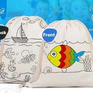 Könnte beinhalten: Eine weiße Kordeltasche mit einem Meeresmotiv. Die Vorderseite der Tasche zeigt einen bunten Fisch mit gelbem Körper, roten und orangen Streifen und einem blauen Schwanz. Die Rückseite der Tasche zeigt ein Segelboot, einen Oktopus, ein Seepferdchen und eine Schnecke. Die Tasche ist aus 100% natürlicher Baumwolle und bereit zum Bemalen.