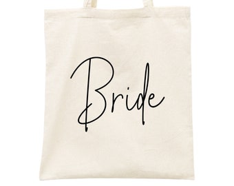 Op de afbeelding: Een witte canvas tote bag met zwarte tekst die "Bride" zegt.