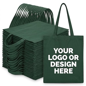 May include: A stack of dark green tote bags with two shoulder straps. One bag stands upright in the foreground, featuring the white text "YOUR LOGO OR DESIGN HERE" printed in the center. The bags are made of a solid fabric with a flat rectangular shape.