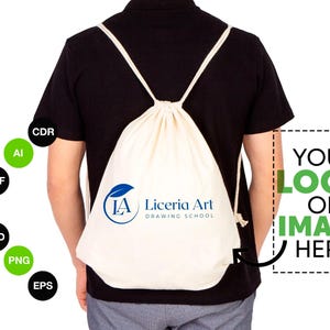 Op de afbeelding: Een witte trekkoordtas met een blauw logo met de tekst "IA Liceria Art Drawing School". De tas wordt gedragen door een persoon, en er is een groene doos met de tekst "YOUR LOGO OR IMAGE HERE" aan de rechterkant van de afbeelding.