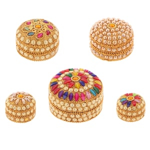 May include: Five decorative boxes with intricate designs. The boxes are made of gold metal and are adorned with colourful beads and jewels. The boxes are perfect for storing small items like jewellery or trinkets.