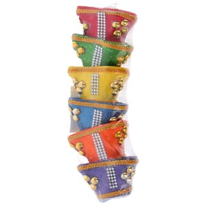May include: A stack of colourful, decorative bowls in a clear plastic package. Each bowl is a different colour: red, green, yellow, blue, orange, and purple. They are adorned with gold-coloured embellishments and a line of silver rhinestones.