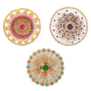 May include: Three circular decorative items with intricate designs. The first is a gold, pink, and white design with a pink flower in the centre. The second is a gold and white design with a purple flower in the centre. The third is a gold, peach, and blue design with a green flower in the centre.