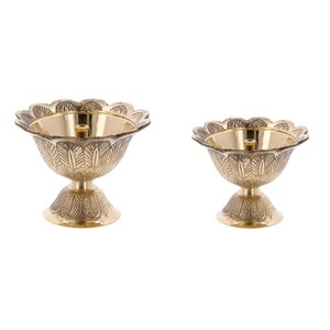 May include: Two gold metal diya oil lamps with intricate floral designs. The diyas have a round bowl shape with a small opening in the centre for a wick.