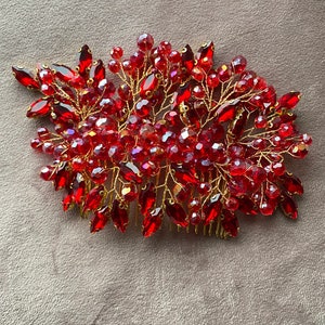 以下が含まれることがあります： 金色のワイヤーとビーズが付いた赤いクリスタル製のヘアコーム。コームは、多くの赤いクリスタルとビーズで花の形にデザインされています。