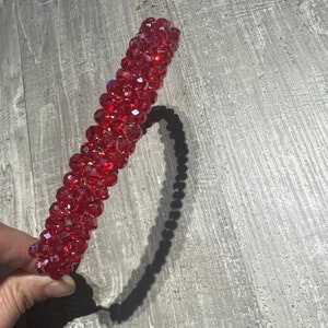 Könnte beinhalten: Ein rotes Stirnband aus facettierten Kristallperlen. Das Stirnband ist flexibel und kann an die meisten Kopfgrößen angepasst werden.