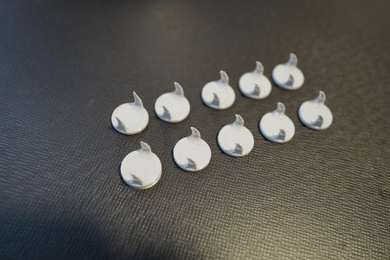 May include: Ten white plastic hooks with a curved design. The hooks are arranged in two rows of five.