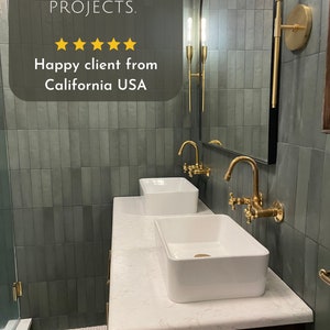 Puede incluir: Un tocador de ba&ntilde;o con dos lavabos de porcelana blanca, grifos dorados y un espejo grande arqueado. Las paredes est&aacute;n revestidas con azulejos verdes oscuros de metro. La encimera es blanca con vetas grises. El tocador est&aacute; hecho de madera oscura.