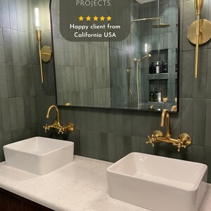 Puede incluir: Dos lavabos de porcelana blanca con grifos dorados est&aacute;n instalados en una encimera blanca con un gabinete de madera oscura debajo. La pared detr&aacute;s de los lavabos est&aacute; alicatada con azulejos verde oscuro. Un gran espejo arqueado sobre los lavabos refleja un ba&ntilde;o con una ducha y azulejos verdes. El espejo tiene una superposici&oacute;n de texto que dice "ONE OF TRIAZA'S PROJECTS." y "Happy client from California USA".