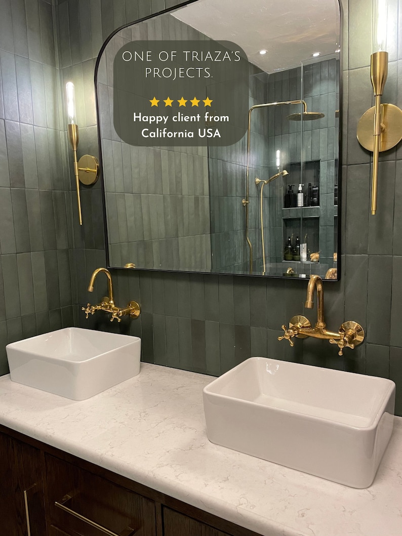 Puede incluir: Dos lavabos de porcelana blanca con grifos dorados est&aacute;n instalados en una encimera blanca con un gabinete de madera oscura debajo. La pared detr&aacute;s de los lavabos est&aacute; alicatada con azulejos verde oscuro. Un gran espejo arqueado sobre los lavabos refleja un ba&ntilde;o con una ducha y azulejos verdes. El espejo tiene una superposici&oacute;n de texto que dice "ONE OF TRIAZA'S PROJECTS." y "Happy client from California USA".