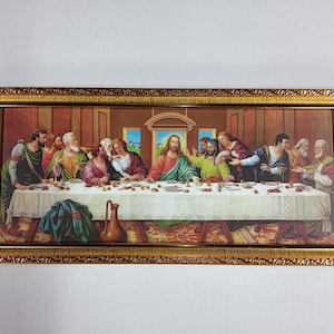 Op de afbeelding: Een ingelijst schilderij dat het Laatste Avondmaal voorstelt, een beroemde bijbelse scène. Het schilderij toont Jezus Christus en zijn discipelen die rond een tafel zijn verzameld, met een gedetailleerde achtergrond en een gouden lijst.