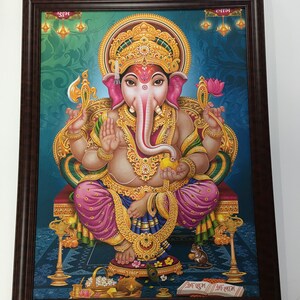 May include: A framed painting of the Hindu deity Ganesha, depicted in a seated position with four arms, holding a lotus flower, an axe, a bowl of sweets, and a book. He is adorned with gold jewelry and a pink and gold robe. The background is a blue and green floral pattern with gold accents. The text "श्री गणेश" is written in the bottom right corner of the painting.
