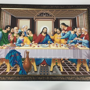 Op de afbeelding: Een ingelijst schilderij dat het Laatste Avondmaal voorstelt, een bijbelse scène met Jezus Christus en zijn discipelen die rond een tafel zitten. Het schilderij is gesitueerd in een kamer met een houten plafond en toont een gedetailleerde weergave van de figuren en hun gezichtsuitdrukkingen.