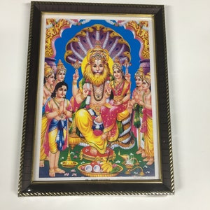 May include: Framed print depicting a Hindu deity with a lion face, surrounded by other figures. The deity is seated on a multi-headed snake, with a blue background and gold accents.