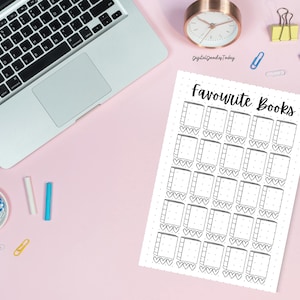 May include: A white paper with the text "Favourite Books" and a grid of book and heart illustrations. A laptop, clock, and office supplies are on a pink desk. The clock shows the time.