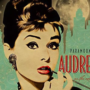May include: Vintage-style poster featuring Audrey Hepburn applying lipstick. The image has a retro aesthetic with a teal background, a full moon, and a city skyline. The text "PARAMOUNT AUDREY" is displayed in red.