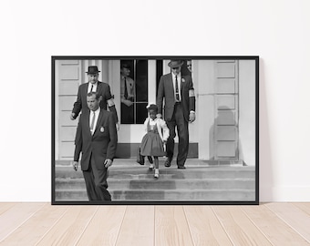 May include: Black and white framed print of a young girl, escorted by men in suits, descending steps. The girl wears a dress and carries a bag. The men wear hats and ties. The image is a historical photograph.