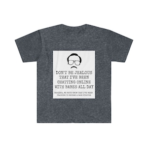 May include: A dark heather grey t-shirt with a white square graphic featuring a cartoon man with glasses and a moustache. The text on the graphic reads "Don't be jealous that I've been chatting online with babes all day. Besides, we both know that I've been training to become a cage fighter."