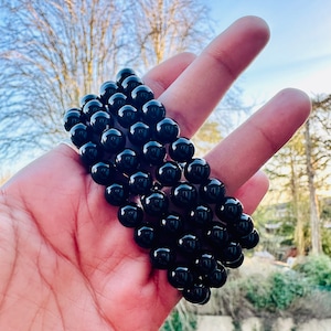 May include: A black beaded bracelet with multiple strands of round beads. The bracelet is made of polished black onyx stones.