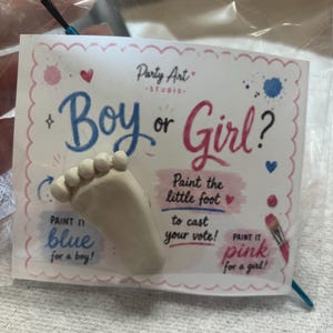 May include: A gender reveal party kit with a small foot-shaped plaster cast. The card reads "Boy or Girl?" with instructions to paint the foot blue for a boy or pink for a girl. Includes a paintbrush.