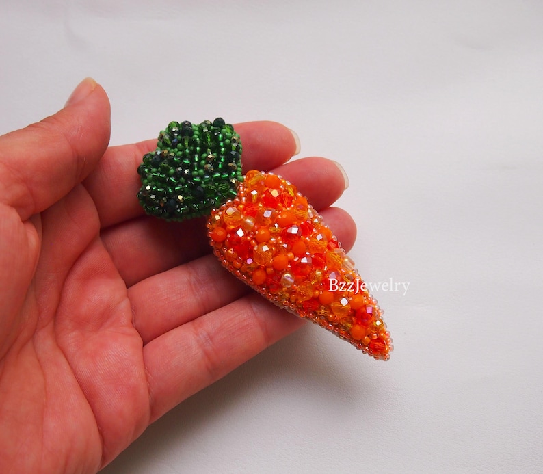 embroidered beaded brooch totally handmade carrot, more than 15 kinds of different kinds beads oforange and green colour. it has pin attachment. itl ooks cool with any clohtes.size is about 7 cm by length and about 3 cm by width.