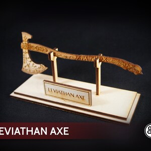 May include: A wooden model of the Leviathan Axe from the video game God of War. The axe is displayed on a wooden stand with a plaque that reads "Leviathan Axe".