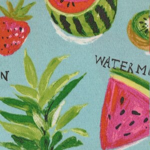 Peut inclure: Un tissu bleu avec un imprim&eacute; de fruits color&eacute;s. L'imprim&eacute; comprend une past&egrave;que, un ananas, une fraise, un kiwi et un citron. Le texte "WATERMELON" est visible sur le tissu.