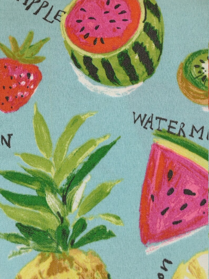 Peut inclure: Un tissu bleu avec un imprim&eacute; de fruits color&eacute;s. L'imprim&eacute; comprend une past&egrave;que, un ananas, une fraise, un kiwi et un citron. Le texte "WATERMELON" est visible sur le tissu.