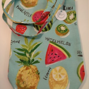Peut inclure: Un sac cabas bleu clair avec une bandouli&egrave;re blanche. Le sac est imprim&eacute; d'un motif de fruits avec de la past&egrave;que, de l'ananas, du kiwi, du citron et des fraises. Les mots "Watermelon", "Pineapple", "Kiwi", "Lemon" et "Strawberry" sont imprim&eacute;s sur le sac.