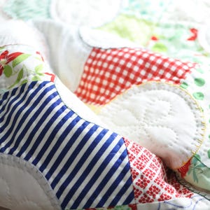 May include: A patchwork quilt with a variety of patterns, including gingham, stripes, polka dots, and floral designs. The quilt is made with white fabric and features a variety of colors, including red, blue, green, and yellow.