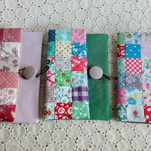 Pode incluir: Uma cole&ccedil;&atilde;o de capas de tecido feitas &agrave; m&atilde;o, cada uma com um design de patchwork &uacute;nico. As capas s&atilde;o em v&aacute;rias cores, incluindo vermelho, rosa, verde e azul, com fechos de bot&atilde;o. Os padr&otilde;es de patchwork incluem desenhos florais e geom&eacute;tricos.