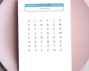 May include: A white card with a pink background and a blue rectangle with the text "TODAY'S THEME Love-ly Day" on it. The card has a word search puzzle with the words "LOVE", "FLOWERS", "HEART", "ROMANCE", "KISSES", "DATE", and "HUGS".