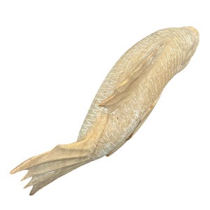 May include: A light brown wooden fish carving featuring a smooth, polished finish and detailed, incised cross-hatch patterns along the body to represent scales. The sculpture displays a curved, elongated shape with a defined tail and fins.