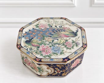 Peut inclure: Une boîte octogonale en céramique ornée d'une illustration détaillée d'un paon au plumage bleu et vert entouré de pivoines roses et bleues sur le couvercle. Les côtés présentent des motifs floraux sur un fond bleu profond.