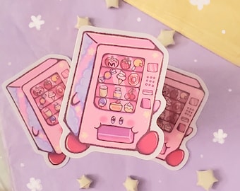 May include: Three pink and white stickers of a cartoon vending machine with a variety of sweets and treats inside. The vending machine has a smiling face and is surrounded by stars.