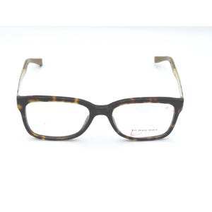 May include: Eyeglasses with a tortoiseshell pattern on the frames and temples. The rectangular frames have a dark brown color, and the temples are a lighter brown. The lenses are clear, and the brand name is visible on the right lens.