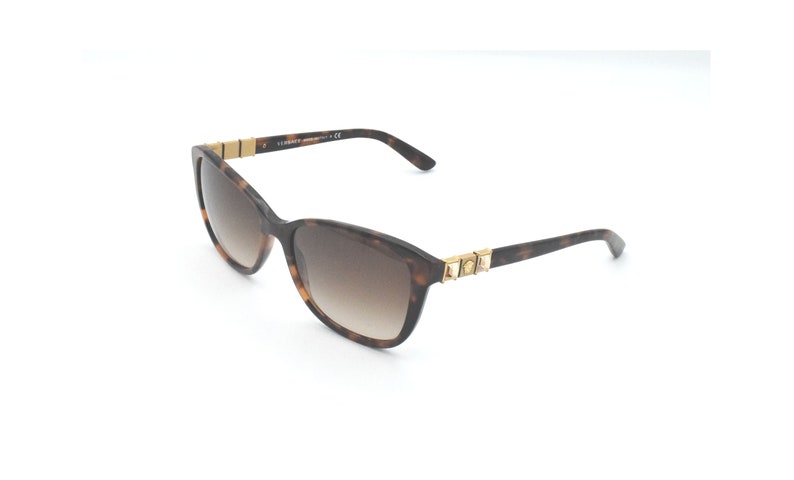 May include: Brown tortoiseshell sunglasses with gold accents and brown gradient lenses. The sunglasses have a Versace logo on the side.