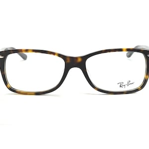 以下が含まれることがあります： べっ甲柄の長方形メガネ。右レンズにはRay-Banのロゴが見えます。フレームは濃い茶色と黄色です。クラシックなデザインです。