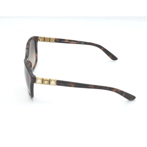 May include: Brown tortoise shell sunglasses with gold accents and a Versace logo on the side.