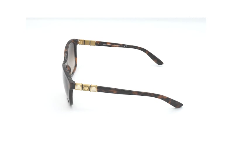 May include: Brown tortoise shell sunglasses with gold accents and a Versace logo on the side.