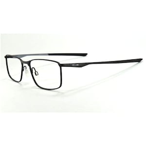 May include: Black rectangular eyeglasses with a thin frame and clear lenses. The temples are slender and extend back from the frame. The brand name is visible on the temple.