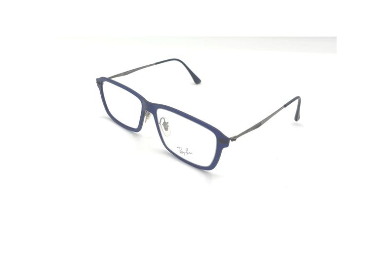 May include: Blue rectangular eyeglasses with dark gray temples. The glasses have a thin frame and the Ray-Ban logo is visible on the lens. The glasses are set against a white background.