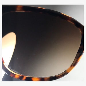 May include: Close-up of a tortoiseshell patterned sunglasses lens with a gradient brown tint.