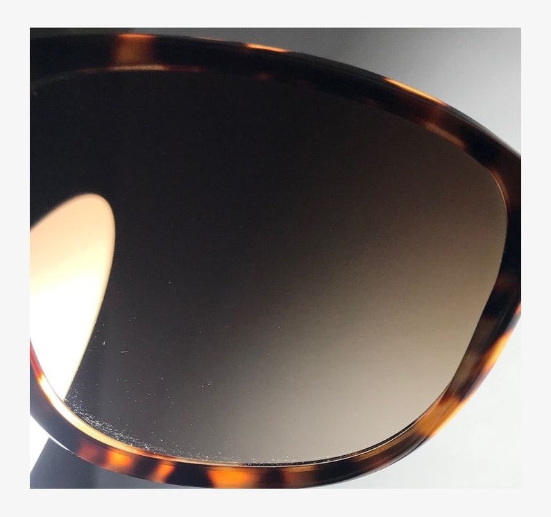May include: Close-up of a tortoiseshell patterned sunglasses lens with a gradient brown tint.
