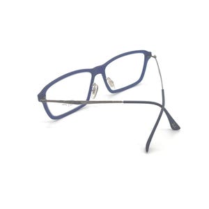 May include: Blue rectangular eyeglasses with silver-toned metal arms and hinges. The glasses have a modern design and are set against a white background. The frames are a matte blue color.